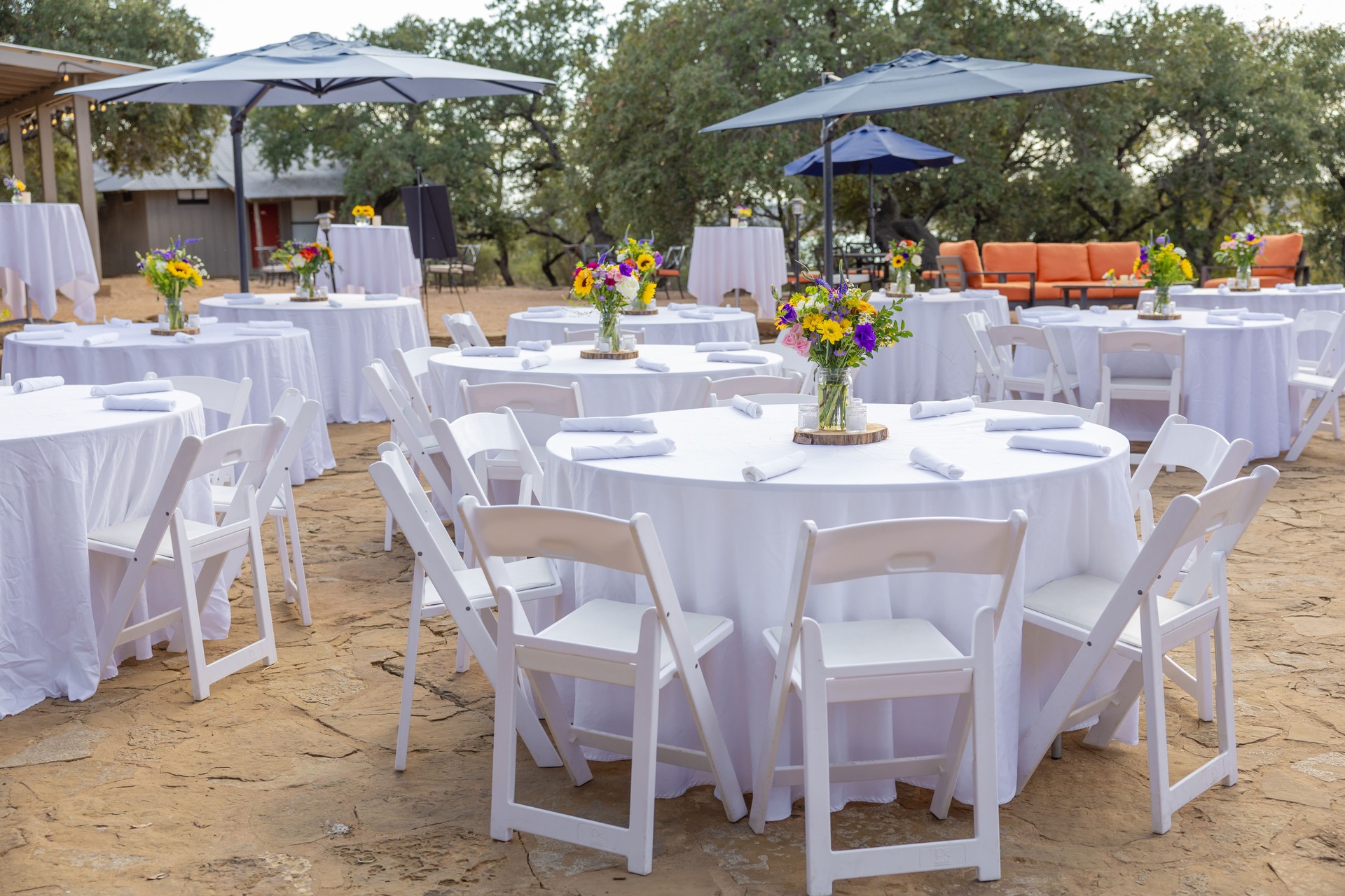 Outdoor event setup with tables and floral centerpieces.