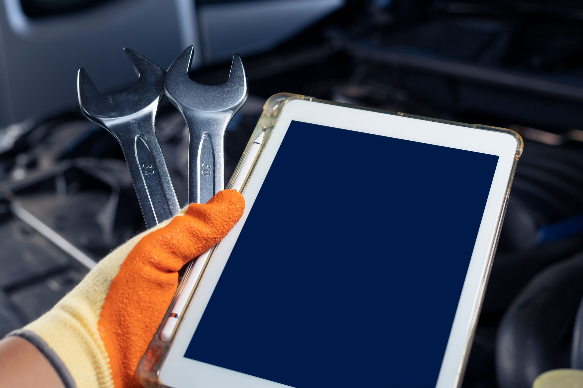Auto mechanic with wrench and tablet for inspection and engine maintenance using modern technology Industry and transportation